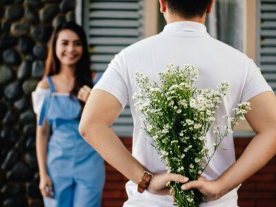 man holding baby s breath flower in front of woman standing near marble wall