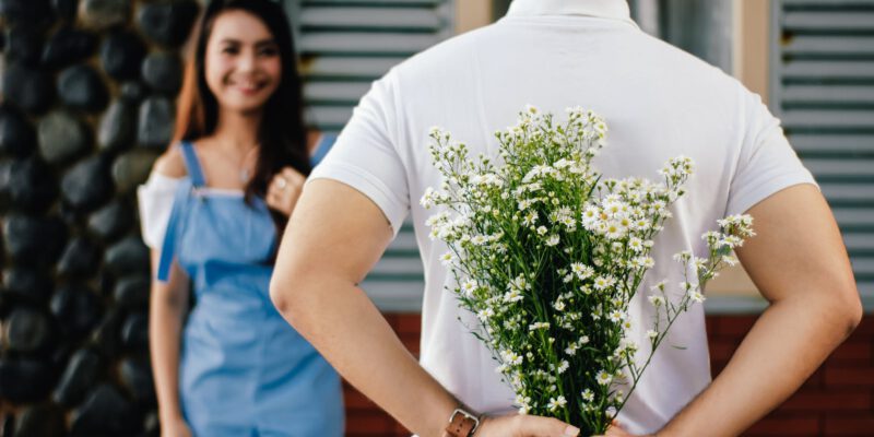 man holding baby s breath flower in front of woman standing near marble wall