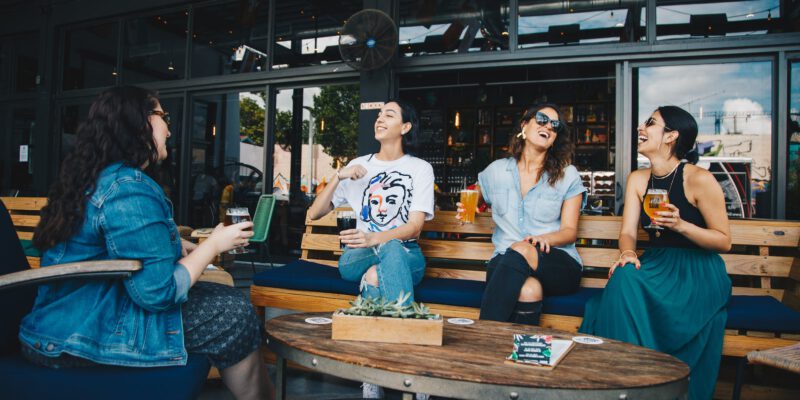 four women chatting while sitting on bench