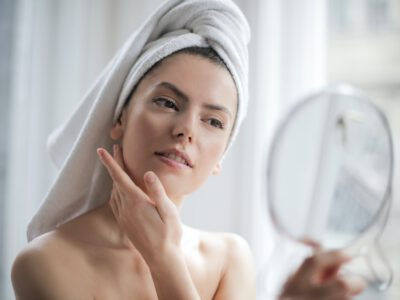 selective focus portrait photo of woman with a towel on head looking in the mirror