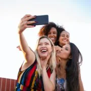 cheerful multiethnic girlfriends taking selfie on smartphone on sunny day